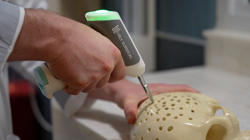 A hand using a drill on a plastic skull.