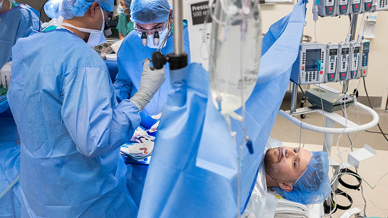 A patient undergoing a kidney transplant surgery while awake with a surgical curtain separating him from the surgical team.
