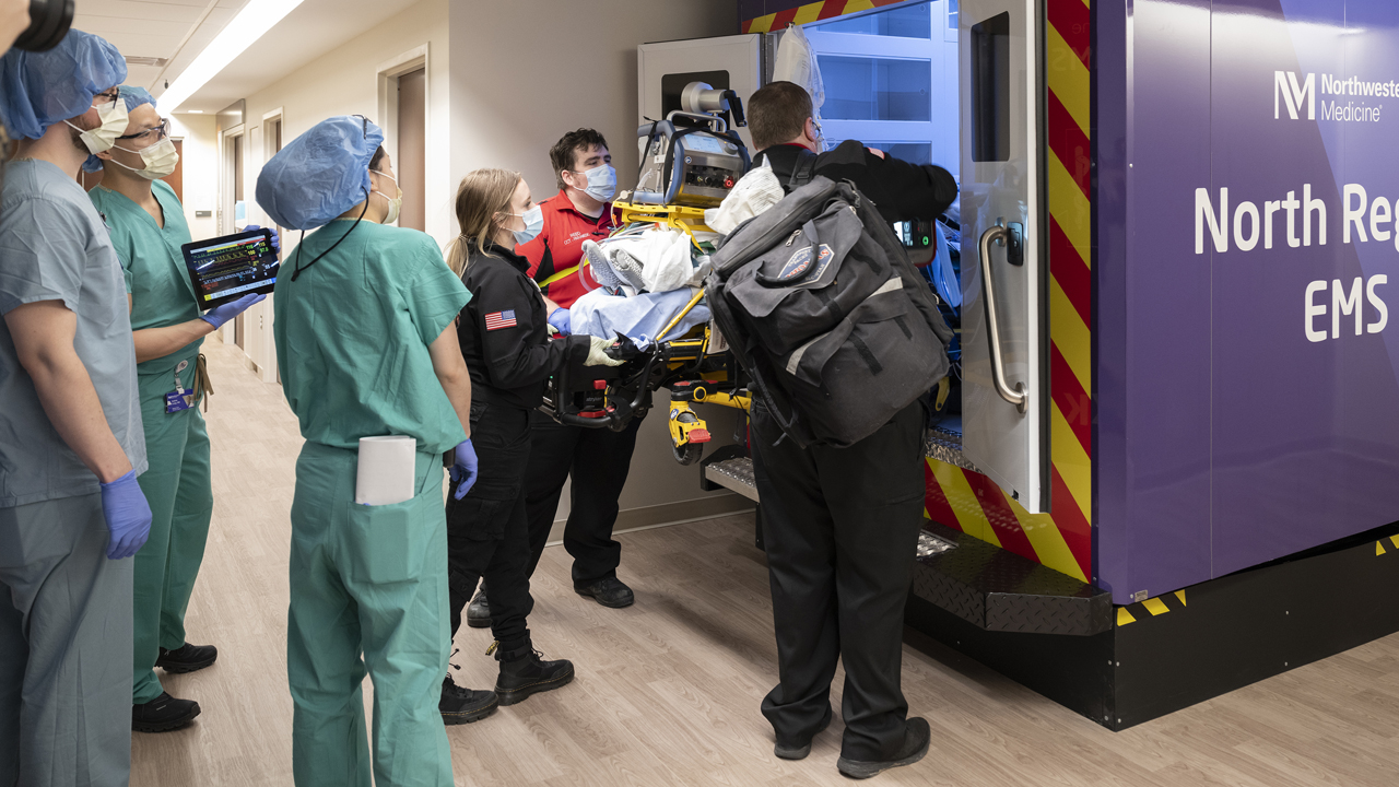 A team of clinicians loads a patient into an ambulance.