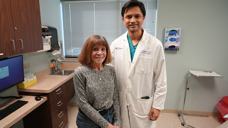 Kathie Schultz wearing a black-and-white shirt standing next to Ankit Bharat, MD, wearing a white physician's coat.