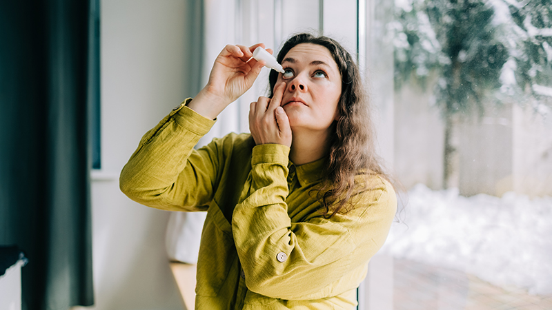 Person putting eyedrops in their eye.