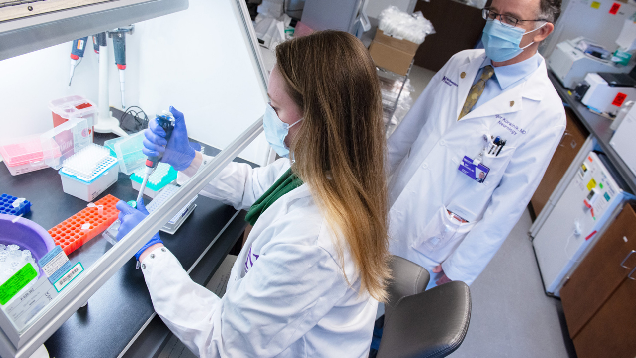 2 people in clinical uniforms in a lab