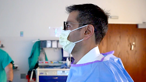 Rajesh Keswani, MD, wears a mask and scrubs while doing a procedure. 