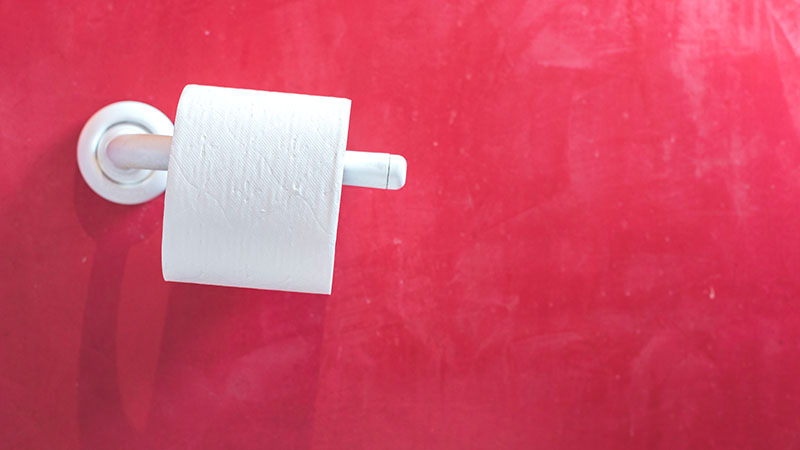 roll of toilet paper against red wall