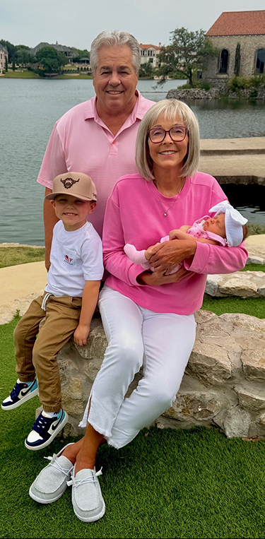 Michelle and her husband, Keith, pose with their grandchildren near water.