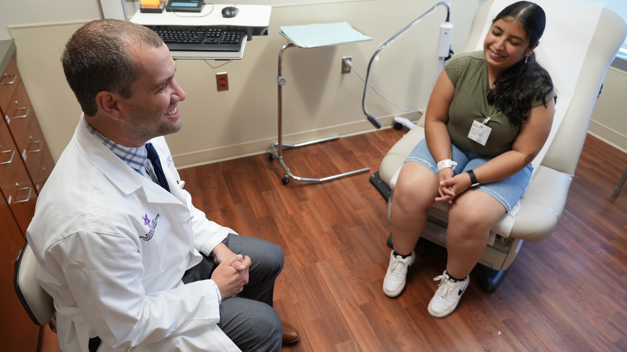 Liliana Castaneda with Dario R. Roque in an exam room.