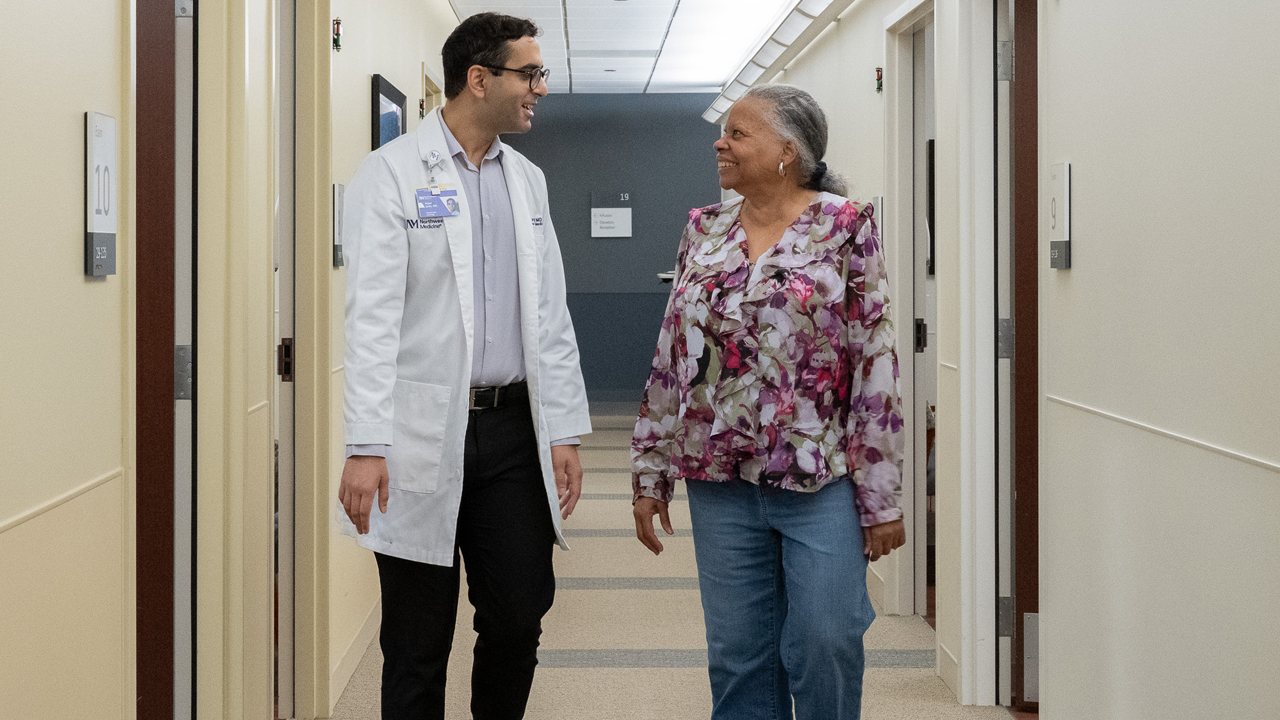 June Furlan speaking with Arjun Seth, MD as they walk down a hospital corridor.