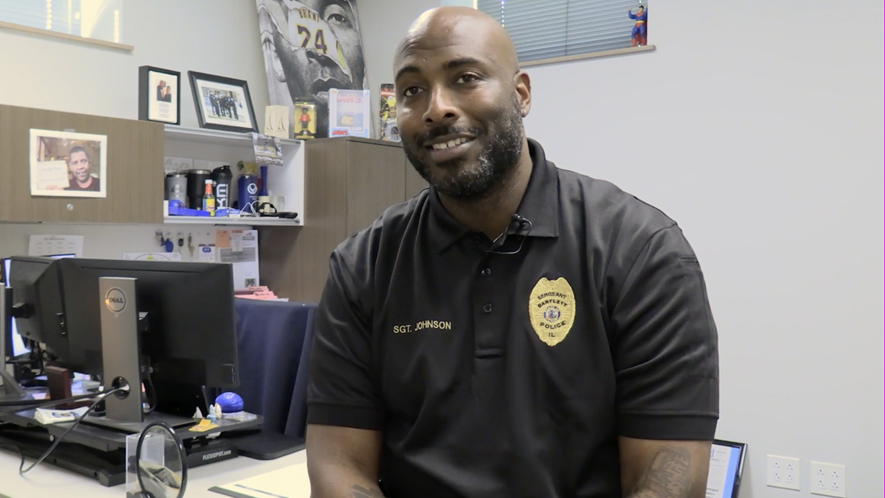Sergeant Chris Johnson sitting on his desk, smiling. 