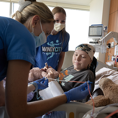 Kendall Schara receiving stem cells via IV while her sister looks on.