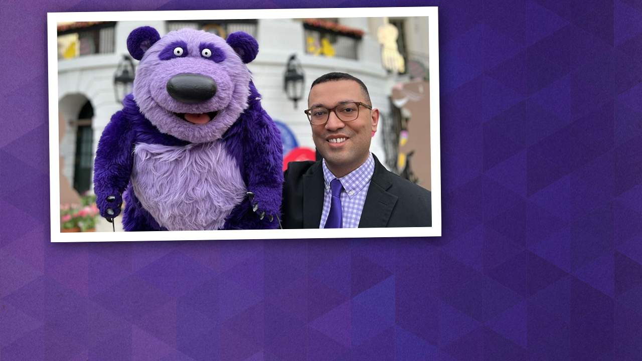 Frankie Cordero holds up a purple bear-like puppet.