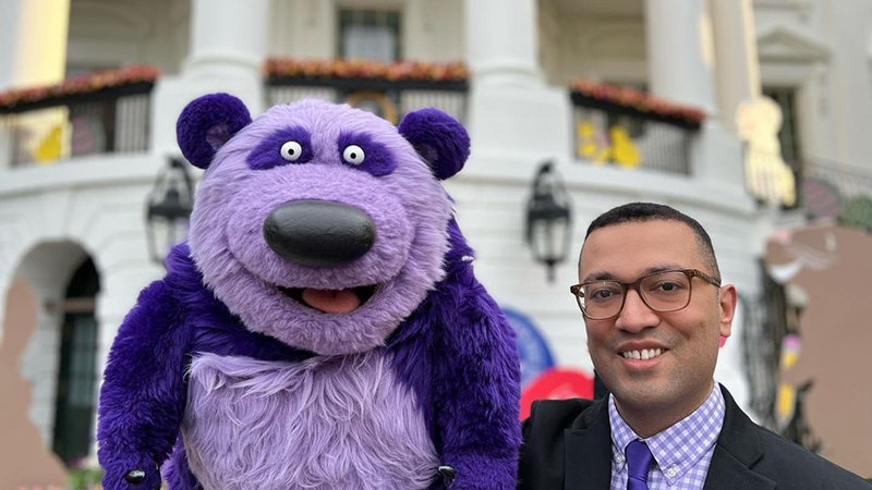 Frankie Cordero holds up a purple bear-like puppet.