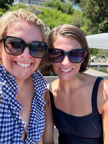 Two women standing together, smiling.