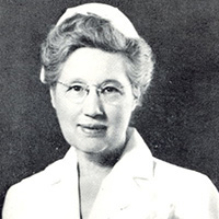 Black and white portrait of Florence Olmstead, RN. She is a white woman in a white nursing cap and dress. She has short hair and glasses.
