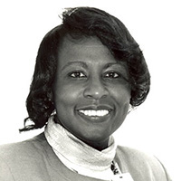 Black and white portrait of Regina Puckett-Kent. She is a Black woman with short hair, wearing a blazer and turtleneck.