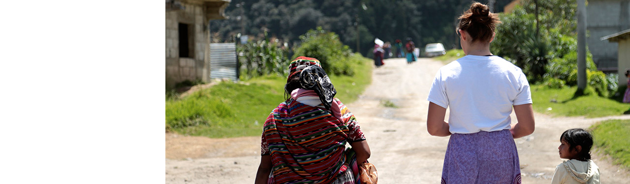 Woman walking with an elderly woman and a child down a dirt path