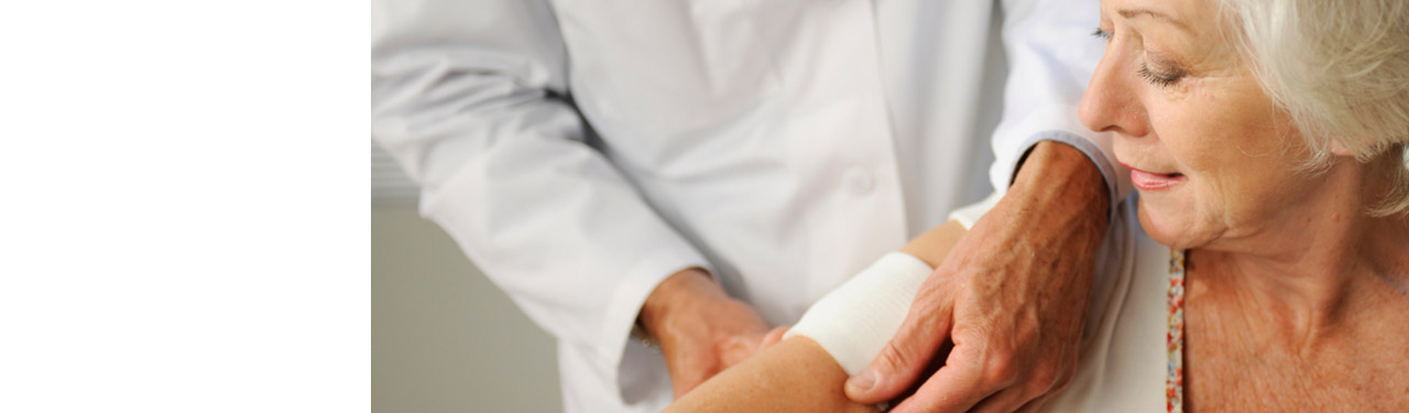Doctor bandaging up an elderly woman's upper arm