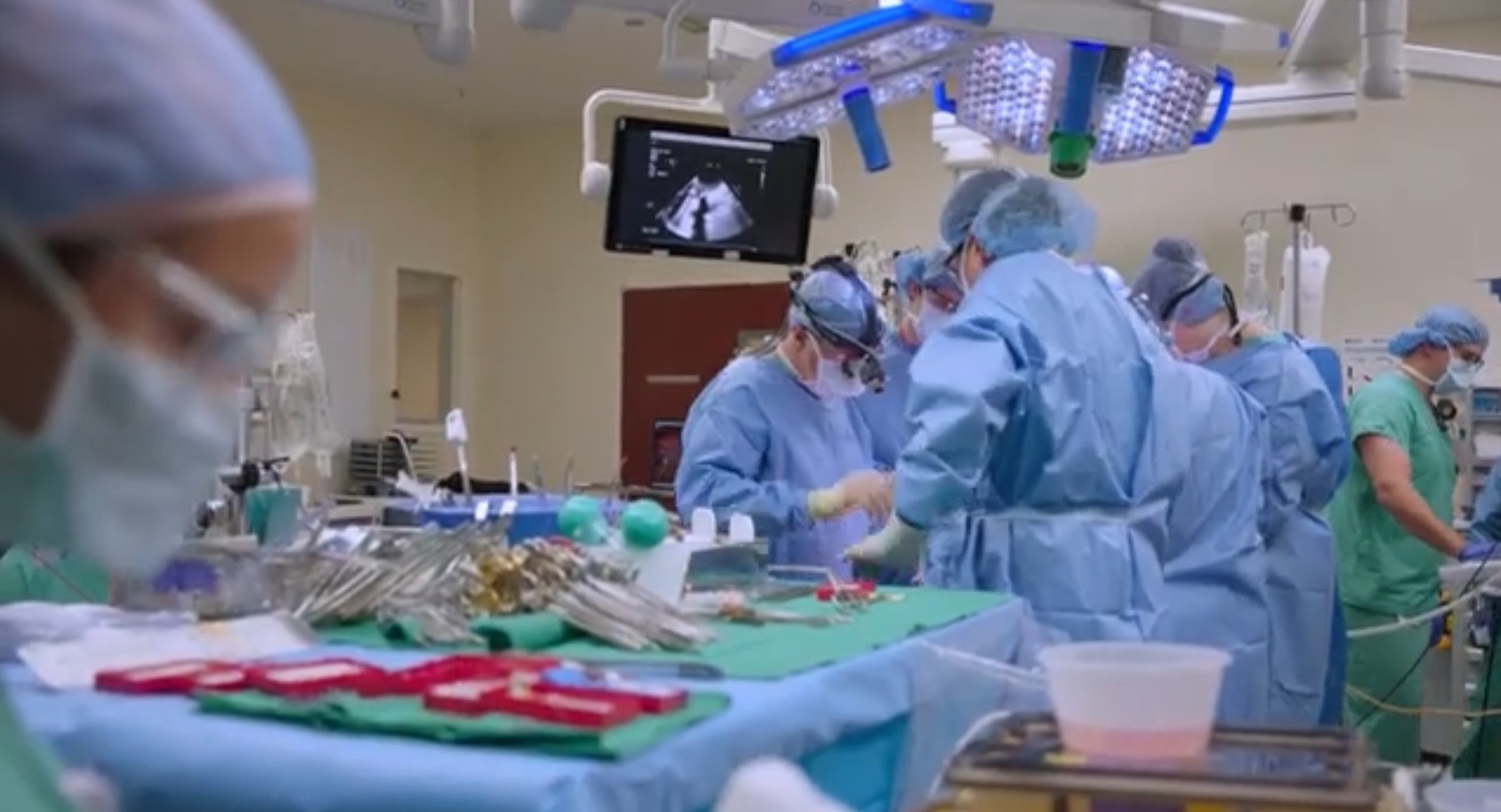 Surgical team performing surgery on a patient in an operating room with surgical tools in the foreground