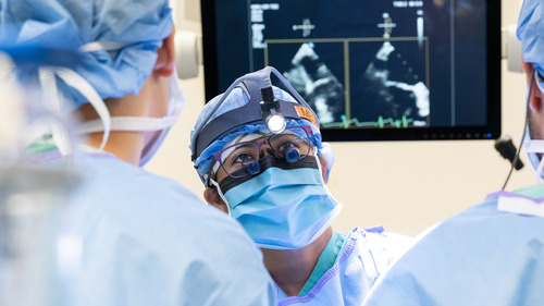 Dr. Melissa Go Medina performing surgery with colleagues in front of an echocardiogram monitor