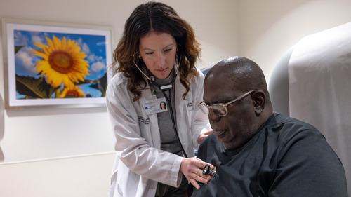 Advanced care provider checks breath sounds of patient with stethoscope in an exam room