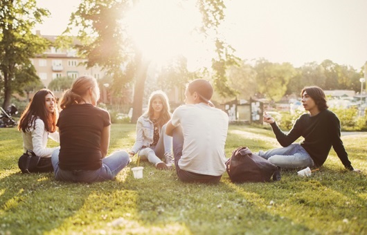 A group of people sitting in the grass on a sunny day.