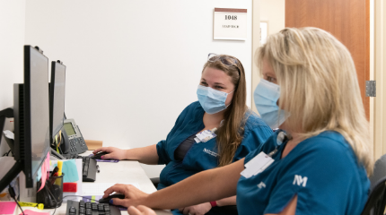Two Northwestern Medicine Breast Health Program nurses looking at imaging on computer screens.