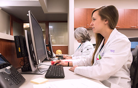 Two physicians with the Head and Neck Cancer Program working at their computers.