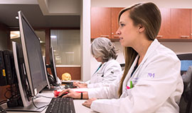 Two head and neck clinic physicians working at their computer stations.