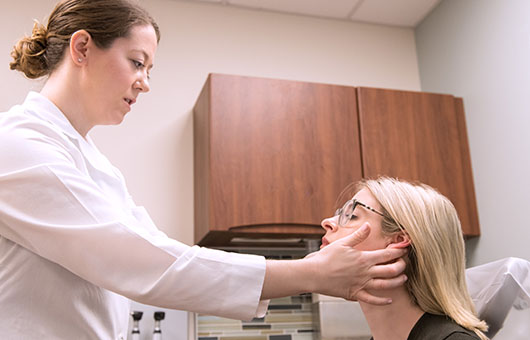 A female physician examining a patient's head and neck.