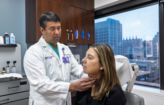 A Northwestern Medicine physician examining the neck of a female patient in a medical office.