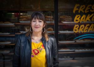 Gabriela stands in front of a bakery storefront