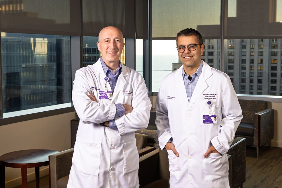Two Northwestern Medicine gastroenterology physicians standing together in a clinical office with city views in the background.
