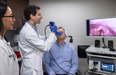 Two Center for Voice physicians examining a patient's throat through a nose camera.