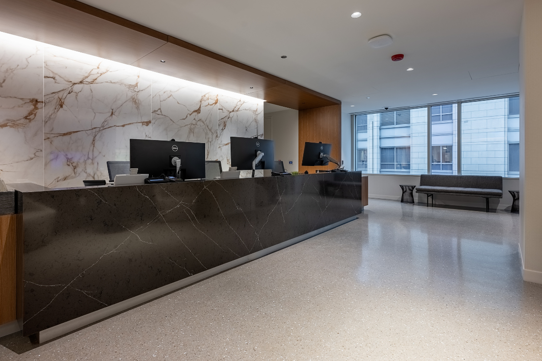 A reception desk in front of a marble wall.