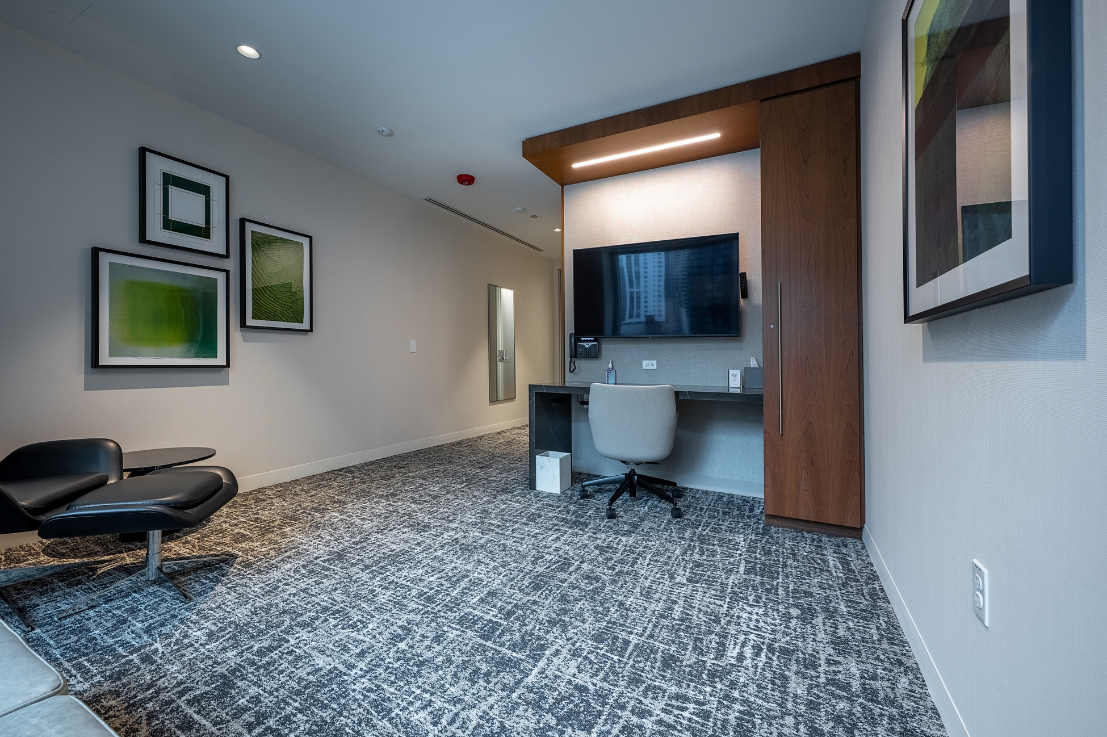 A room with a desk, television and chair.