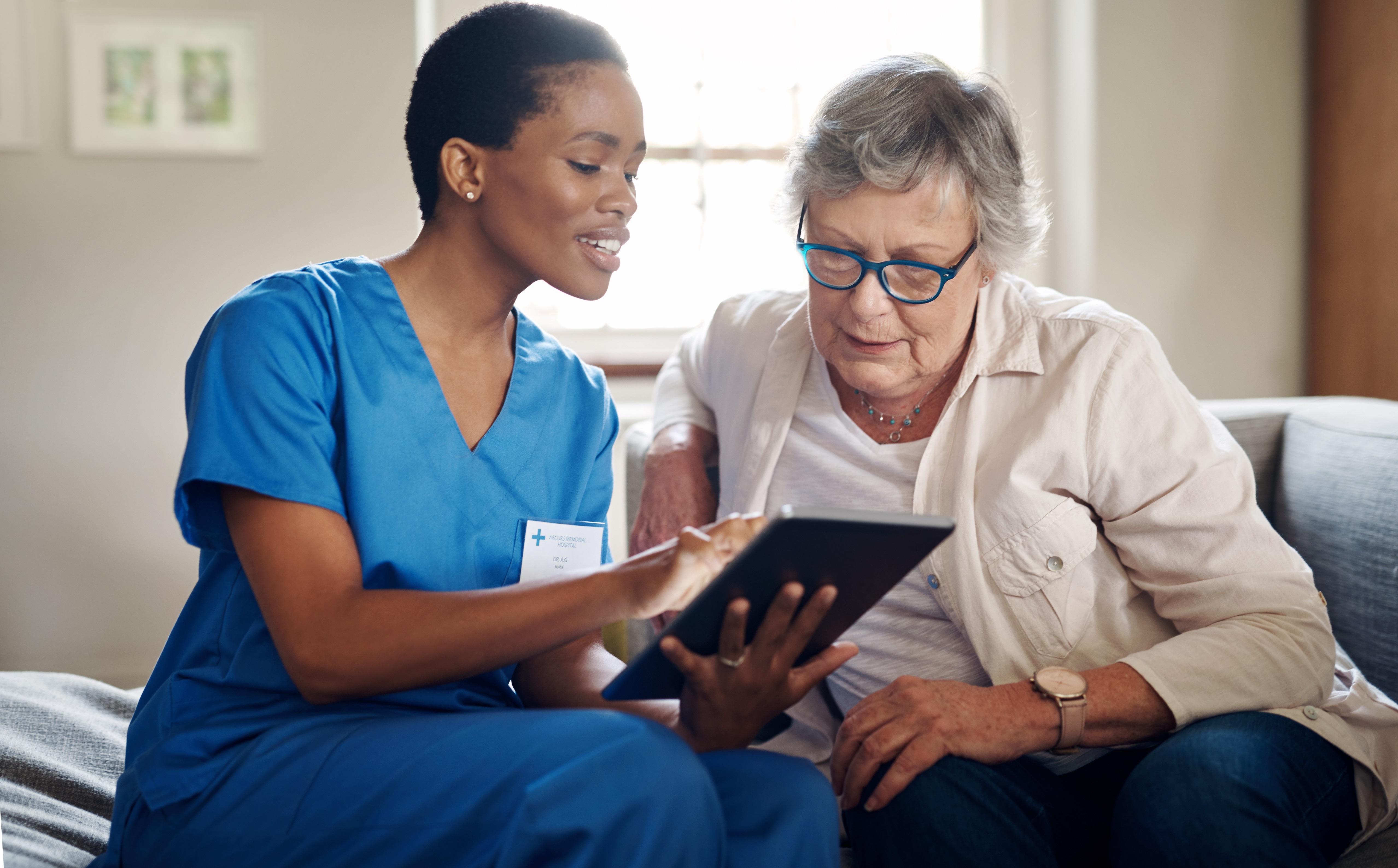 care provider reviews ipad with patient at home