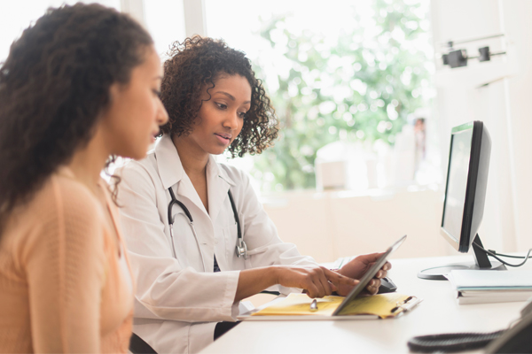 Physician reviewing results on a tablet with a patient