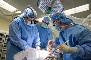 Surgeons wearing scrubs operating on a patient.