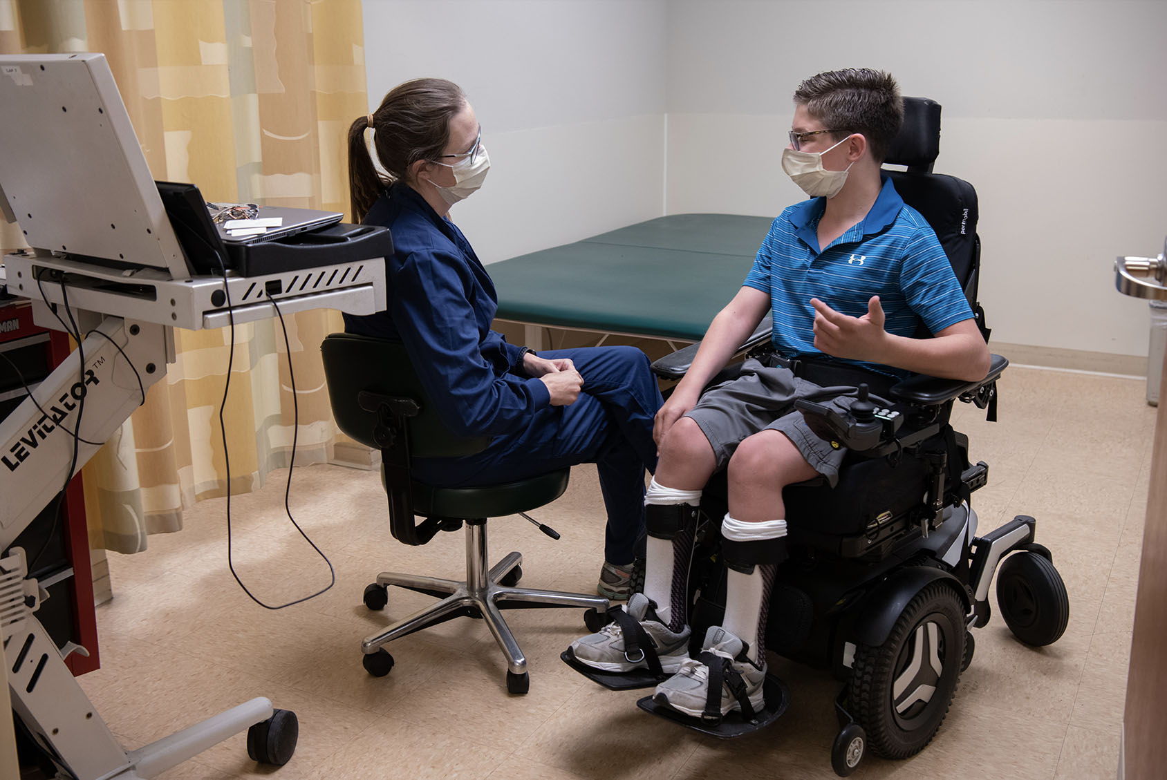 Clinician talking to patient in a wheelchair.