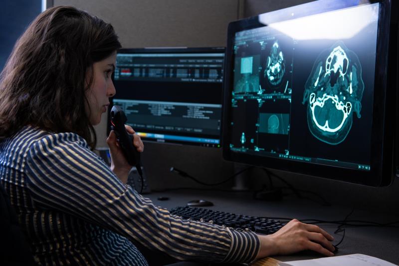 Clinician looking at an image of a brain on a computer screen