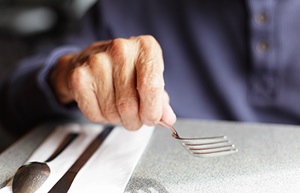 Elderly hand holding a fork.