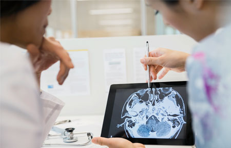 A movement disorders physician discussing a brain scan with another physician.