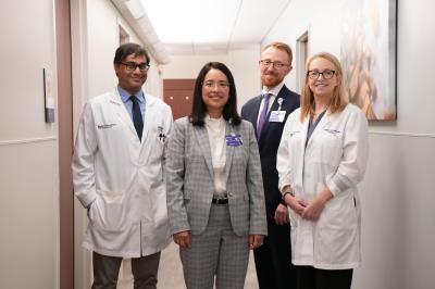 Clinical team of four physicians standing in a hospital hallway.