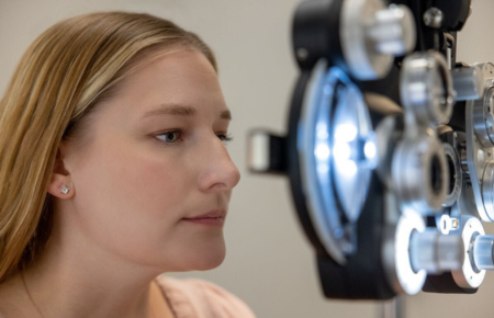 A young female with blonde hair having her eyes examined.