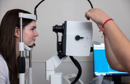 A young woman having her eyes examined by an ophthalmology test.