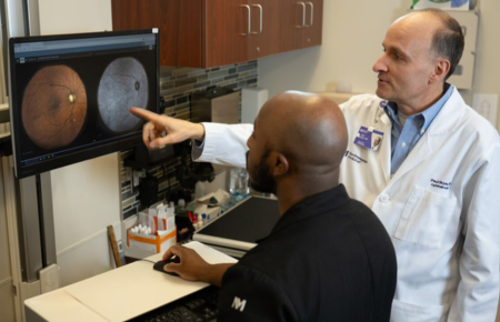 Doctor Paul Bryar pointing at a medical image of an eye on a computer screen.