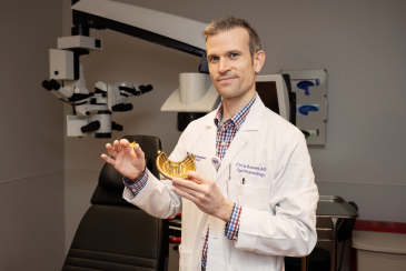 Doctor Randy Bowen Ocular Oncologist holding a gold model of an eye.
