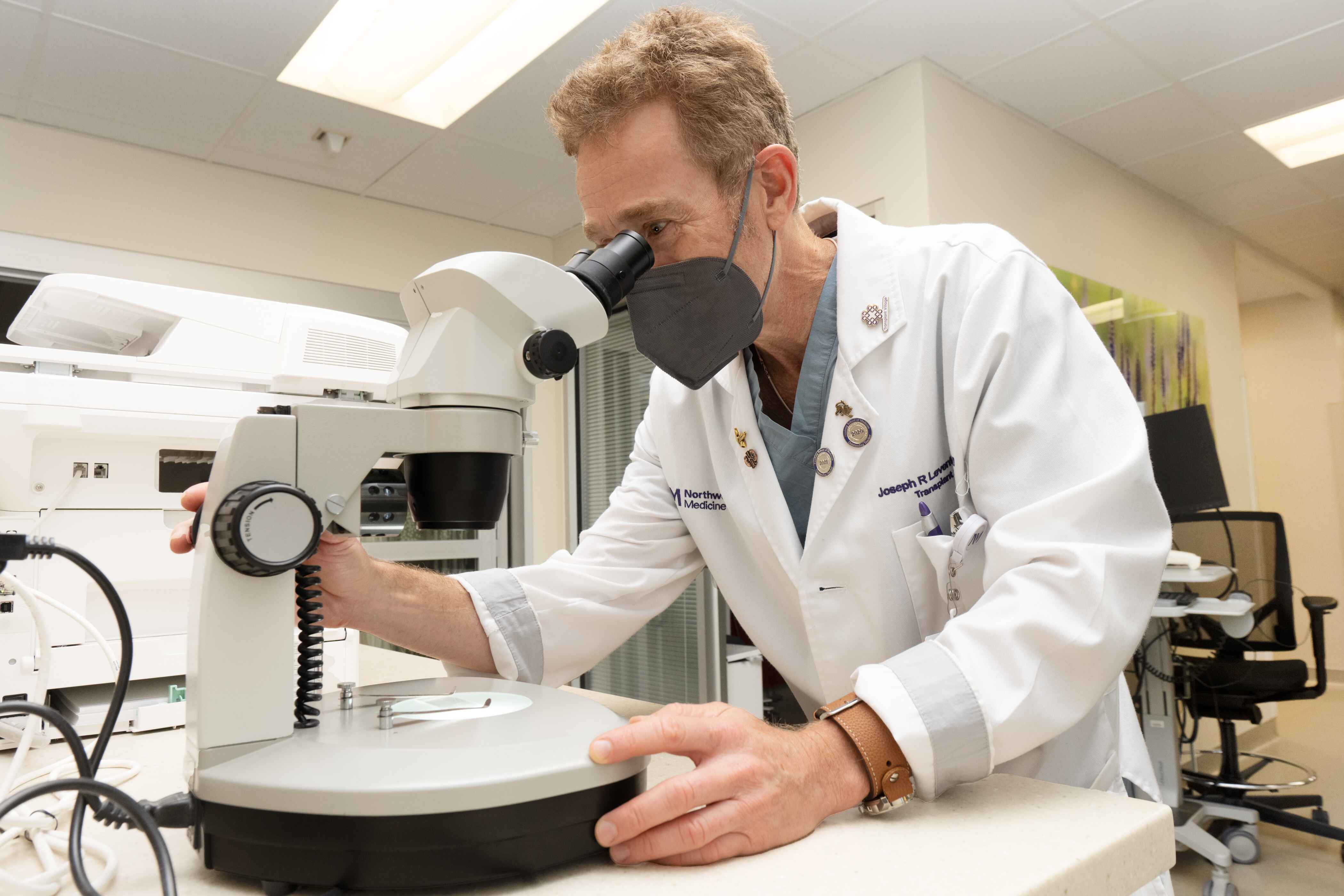 Man in a lab coat looking into a microscope