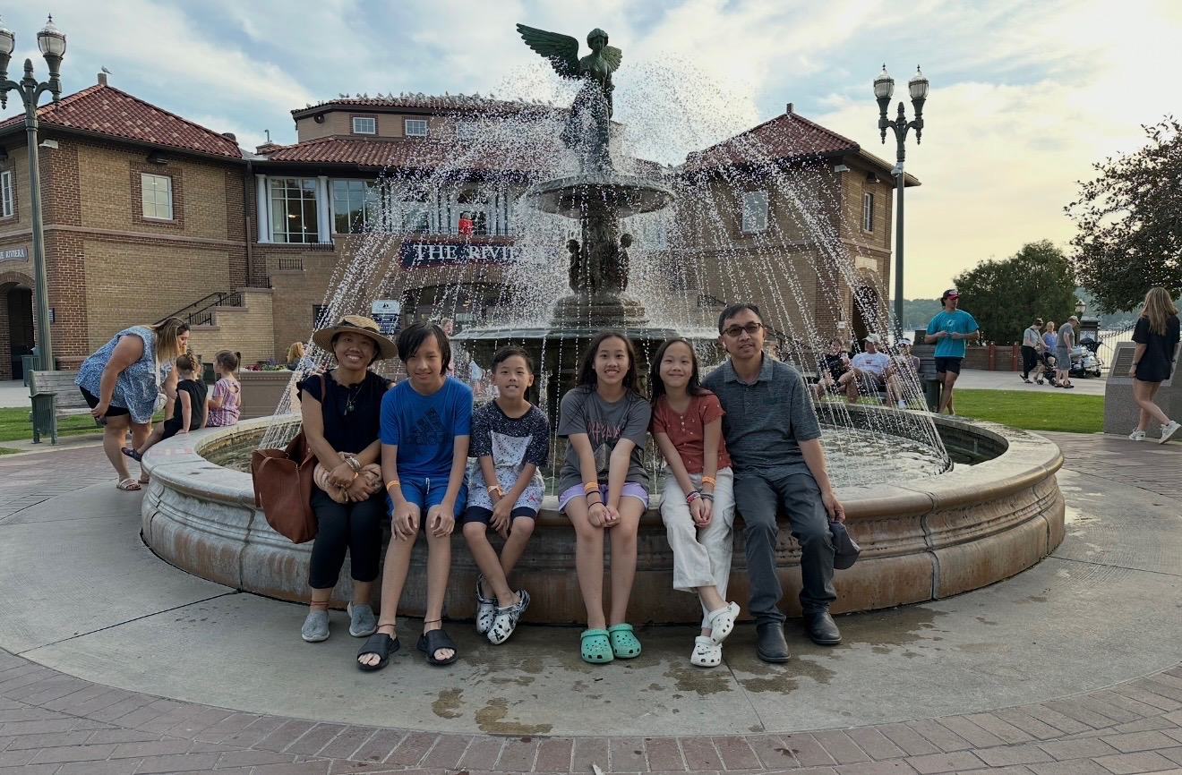 Lung transplant recipient and family seated in front of a fountain during an outdoor community outing.