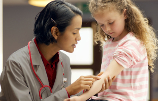Doctor pointing to arm on young patient