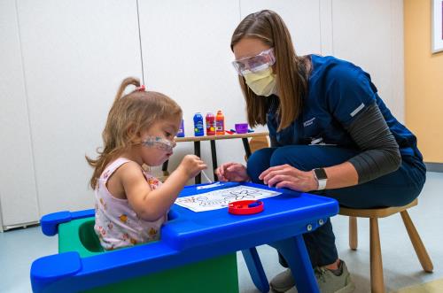 Pediatric rehabilitation specialist and child painting.